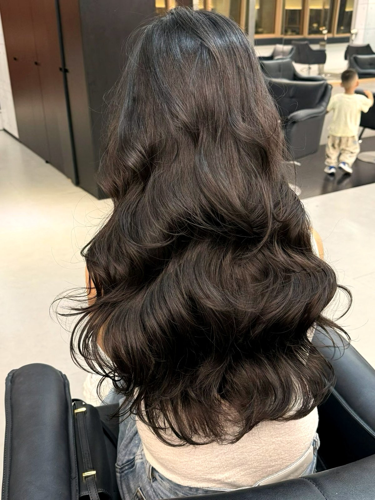 Long dark brown hair finished in soft waves at the salon